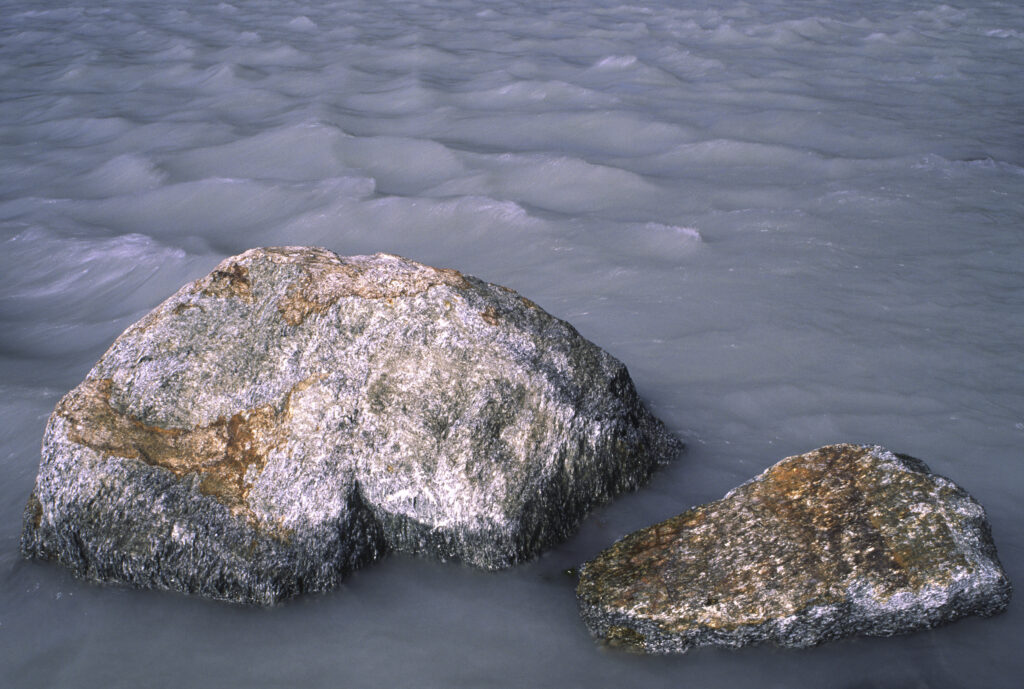 NEW ZEALAND, West Coast, Westland National Park. Rocks located in river coloured by glacial flour downstream of franz josef glacier