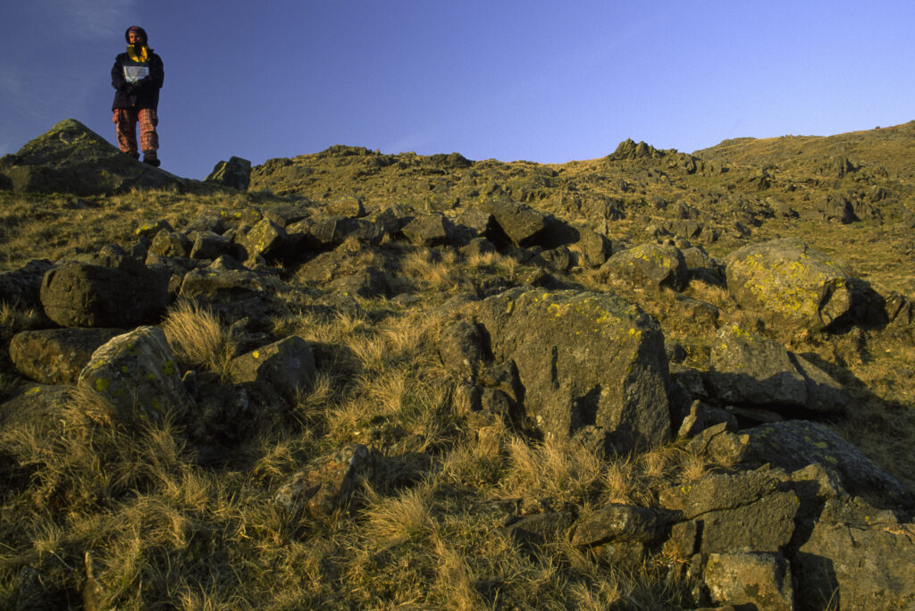 ENGLAND, Cumbria, Lake District National Park. Female hiker watching the sunset from Martcrag Moor on the Cumbria Way