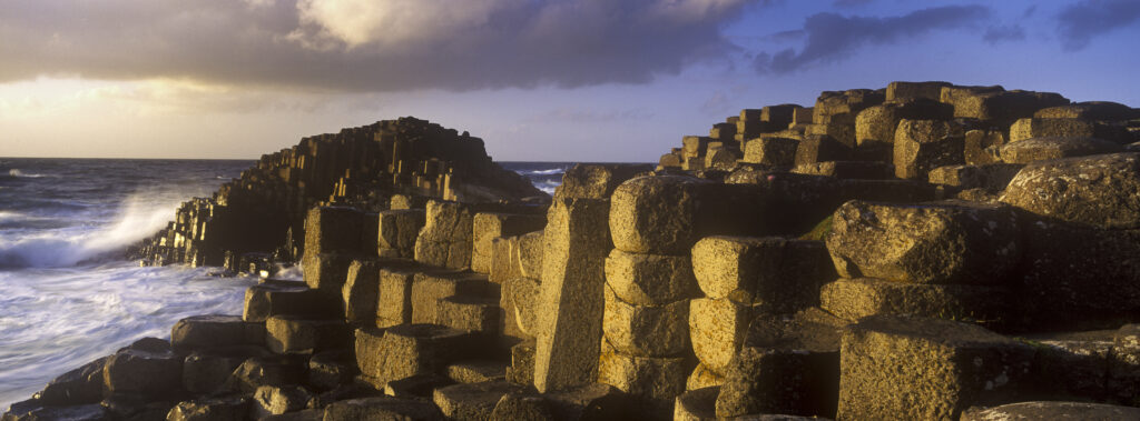 NORTHERN IRELAND, County Antrim, Giants Causeway. Waves crash against the hexagonal basalts rock formations of this world heritage site.