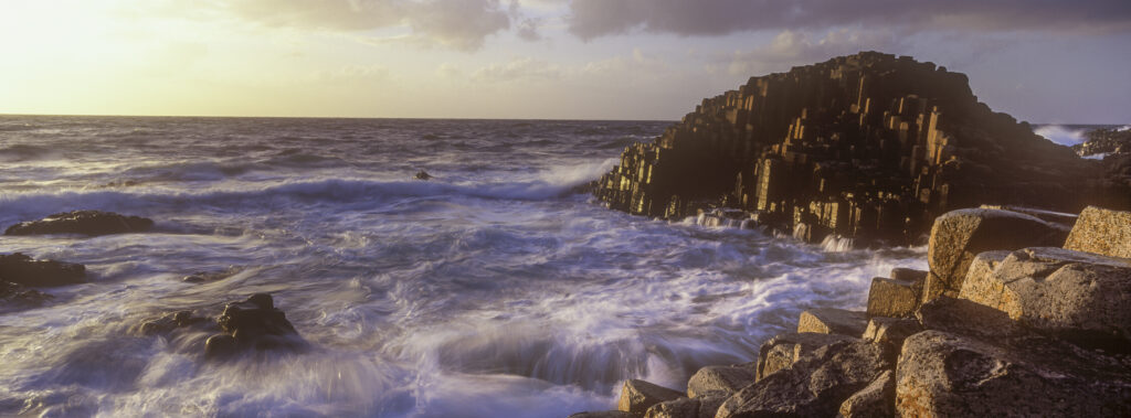 NORTHERN IRELAND, County Antrim, Giants Causeway. Waves crash against the hexagonal basalts rock formations of this world heritage site.