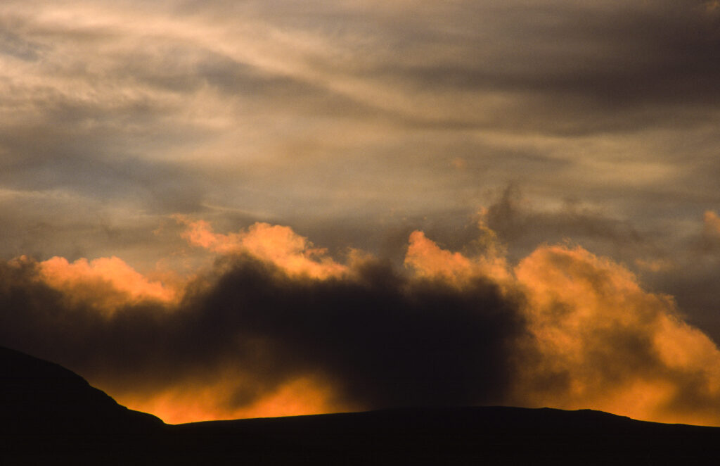 SCOTLAND, Dumfries & Galloway, Galloway Forest Park. The rising sun iluminates clouds over the hills near to Glen Trool.