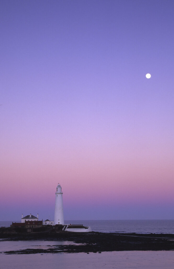 ENGLAND, Tyne & Wear, St Marys Island. The popular landmark of the St Marys Island lighthouse photographed in January against a natural backdrop of a pink sky.