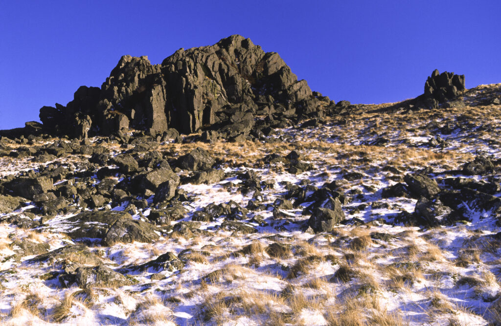 ENGLAND, Northumberland, Northumberland National Park. A rocky outcrop found high above Harthope Valley, surrounded by a fresh snowfall.