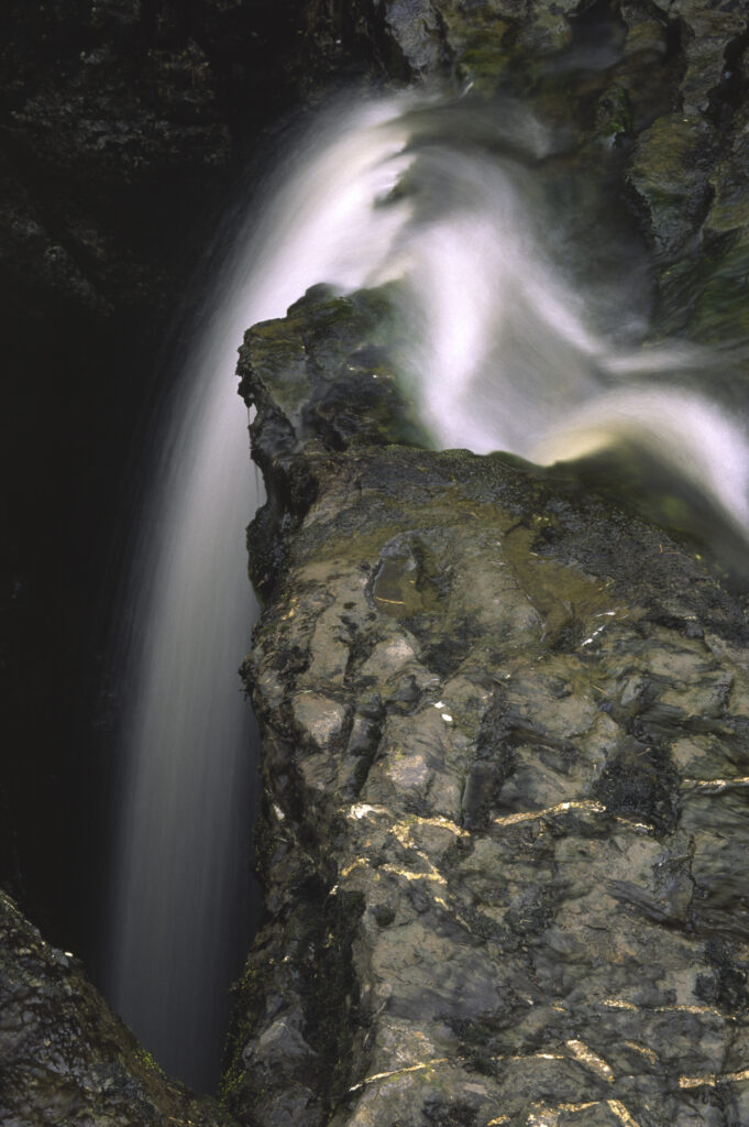 ENGLAND, Yorkshire, Yorkshire Dales National Park. A flowing stream drops into an underground cave system
