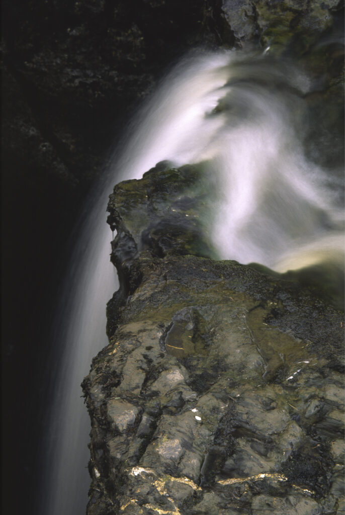 ENGLAND, Yorkshire, Yorkshire Dales National Park. A flowing stream drops into an underground cave system