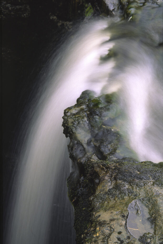 ENGLAND, Yorkshire, Yorkshire Dales National Park. A flowing stream drops into an underground cave system