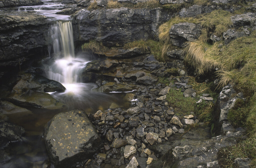 ENGLAND, Yorkshire, Yorkshire Dales National Park. A small waterfall found just before the stream plunges into a cave