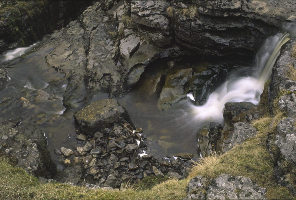 ENGLAND, Yorkshire, Yorkshire Dales National Park. A small waterfall found just before the stream plunges into a cave