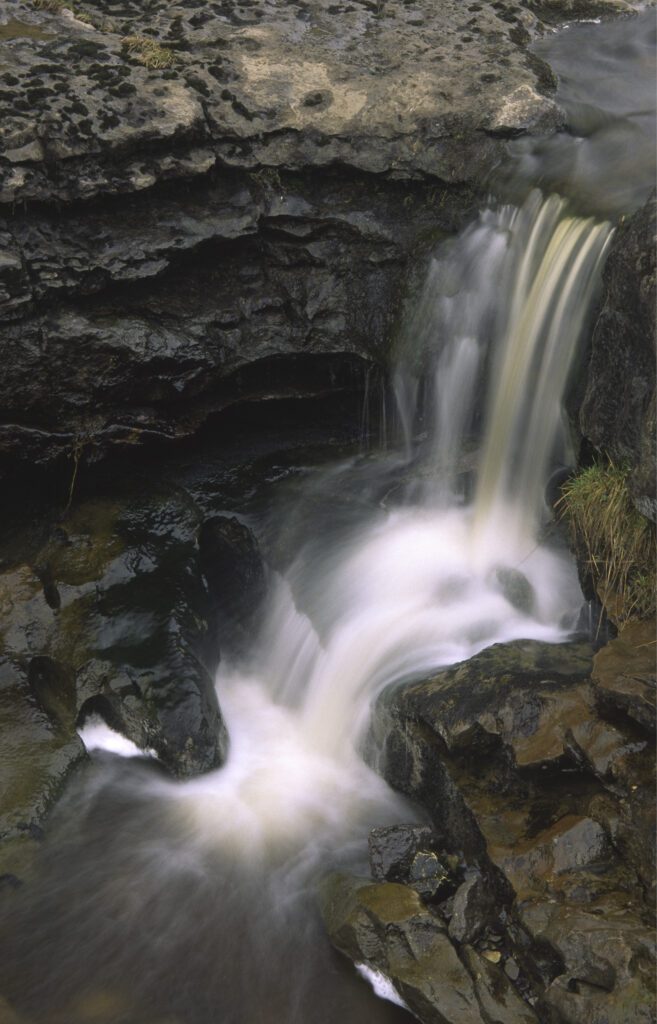 ENGLAND, Yorkshire, Yorkshire Dales National Park. A small waterfall found just before the stream plunges into a cave