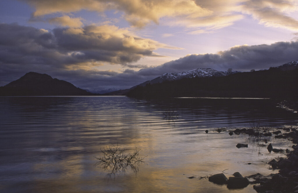 SCOTLAND, Scottish Highlands, Loch Laggan. A storm clears behind the peaks surrounding the still waters of the loch.