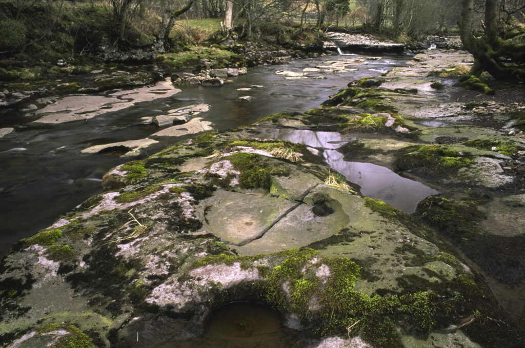 ENGLAND, Yorkshire, Yorkshire Dales National Park. The flowing waters and dry limestone river bed of the river Dee.