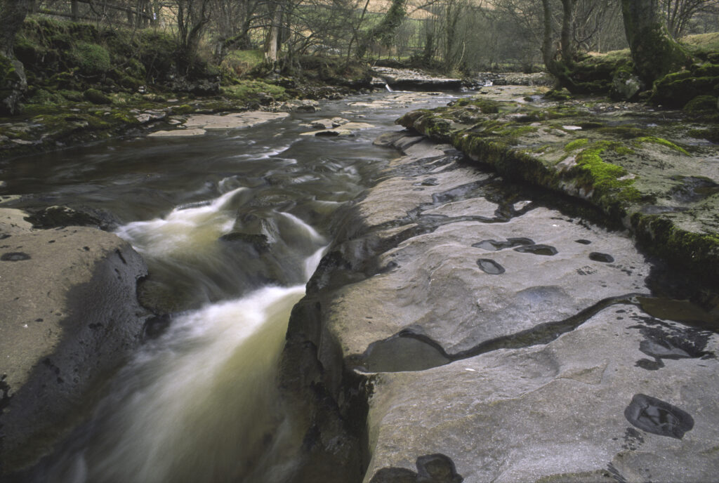 ENGLAND, Yorkshire, Yorkshire Dales National Park. The flowing waters and dry limestone river bed of the river Dee.