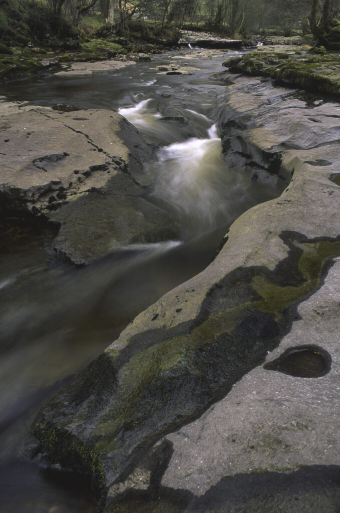 ENGLAND, Yorkshire, Yorkshire Dales National Park. The flowing waters and dry limestone river bed of the river Dee.