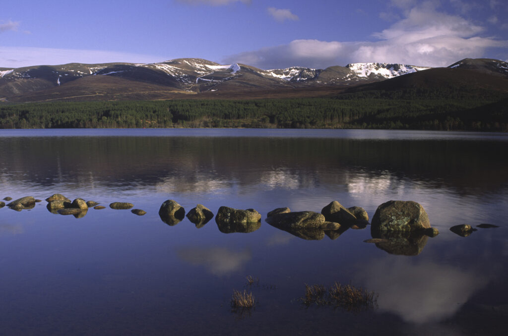 SCOTLAND, Scottish Highlands, Cairngorms National Park. The Cairngorm mountain range reflected in still waters of Loch Morlich
