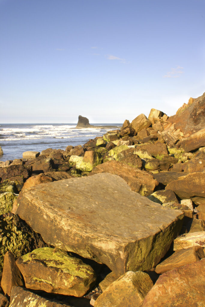 ENGLAND, Yorkshire, North York Moors National Park. Evening light iluminates the boulders of Saltwick Bay near Whitby