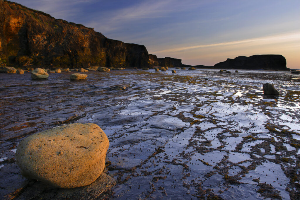 ENGLAND, Yorkshire, North York Moors National Park. Morning light iluminates the coastline of Saltwick Bay and Nab near Whitby
