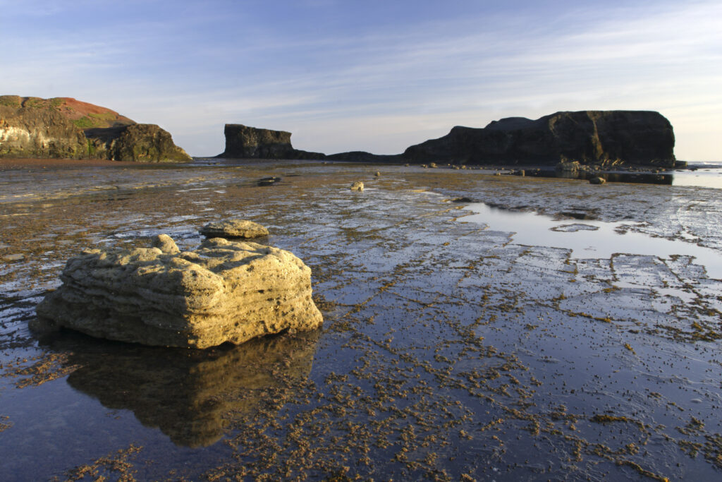 ENGLAND, Yorkshire, North York Moors National Park. Morning light iluminates the coastline of Saltwick Bay and Nab near Whitby