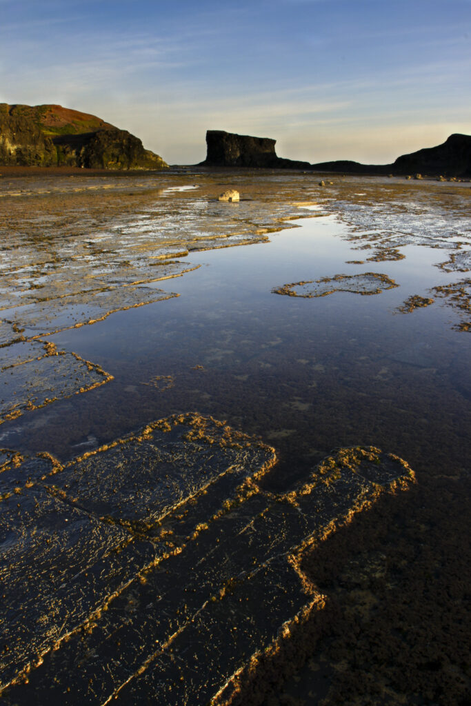 ENGLAND, Yorkshire, North York Moors National Park. Morning light iluminates the coastline of Saltwick Bay and Nab near Whitby