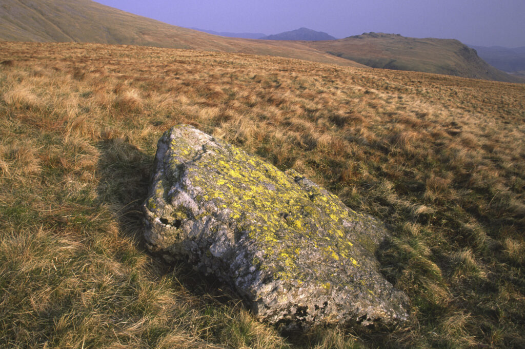 ENGLAND, Cumbria, Lake District National Park. Early evening light illuminates the scattered rocks found on the lower side of scafell