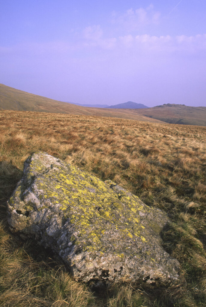 ENGLAND, Cumbria, Lake District National Park. Early evening light illuminates the scattered rocks found on the lower side of scafell