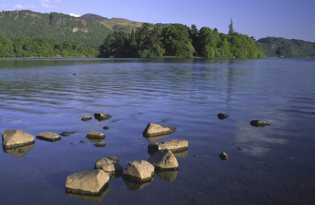 ENGLAND, Cumbria, Lake District National Park. The setting sun illuminates the lakeside and islands of Derwentwater nr Keswick