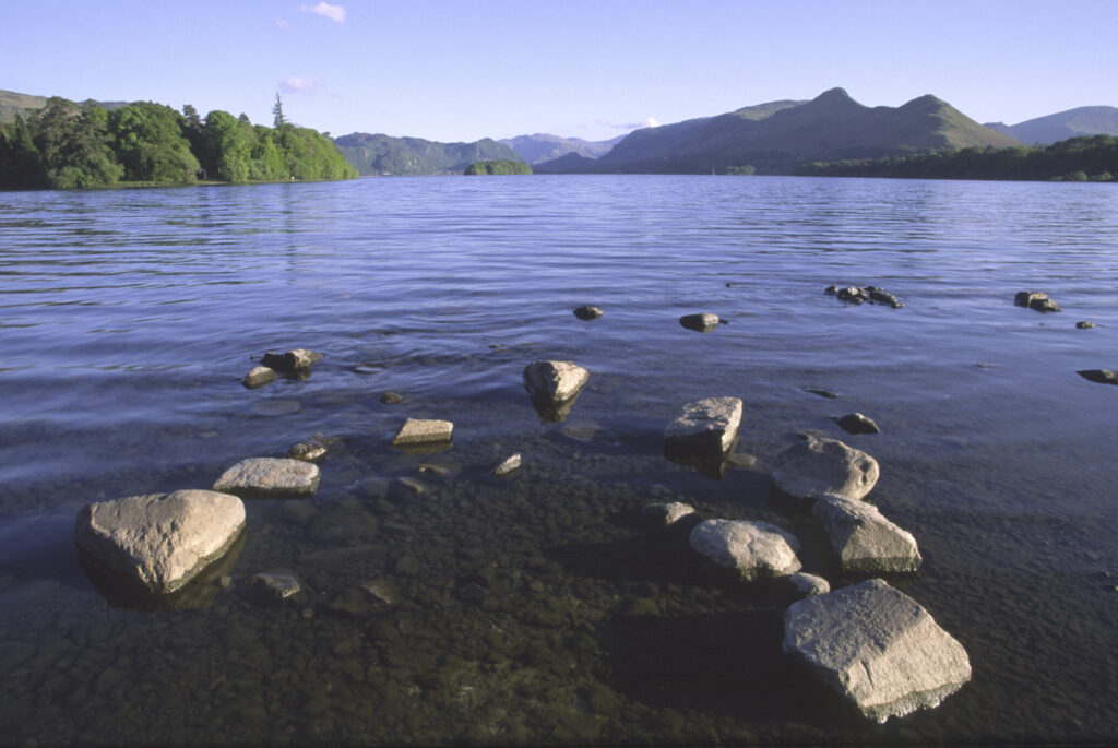 ENGLAND, Cumbria, Lake District National Park. The setting sun illuminates the lakeside and islands of Derwentwater nr Keswick