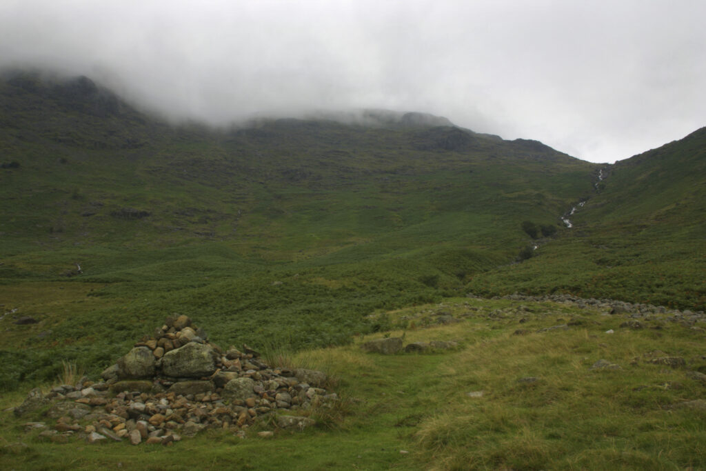 ENGLAND, Cumbria, Lake District National Park. A cairn marks the route near the fast flowing waters of the Stake Gill flowing from Stake Pass near Langdale, on the Cumbria Way.