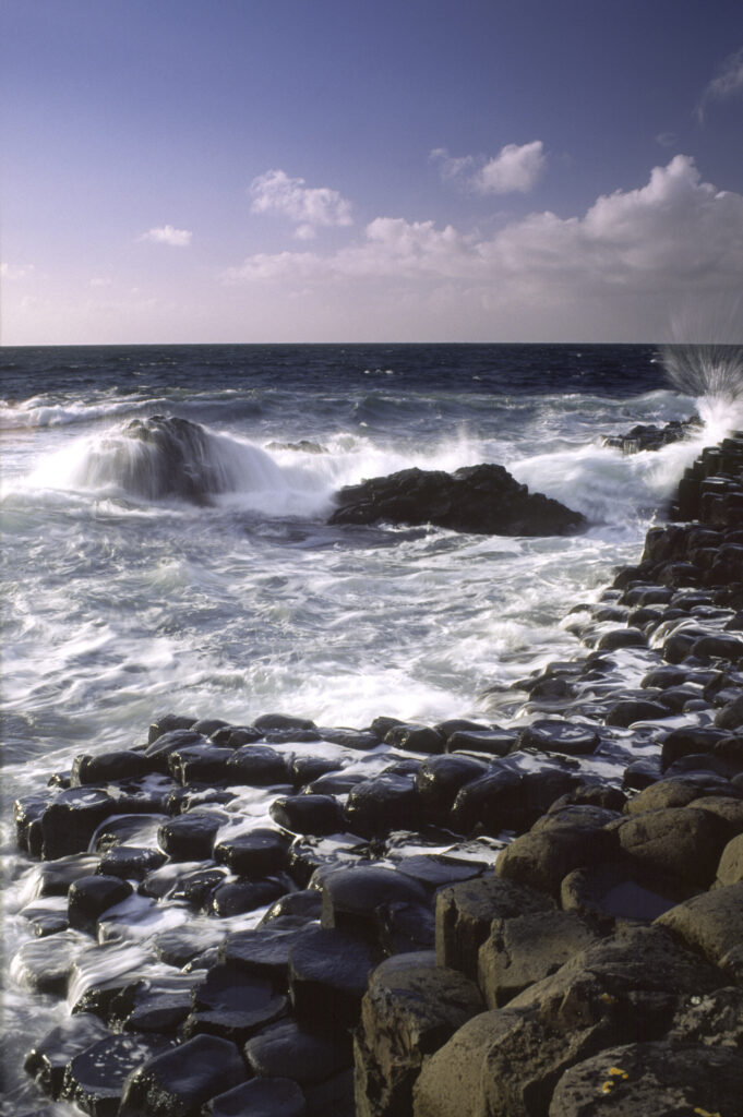 NORTHERN IRELAND, County Antrim, Giants Causeway. Waves crash against the hexagonal basalts rock formations of this world heritage site.