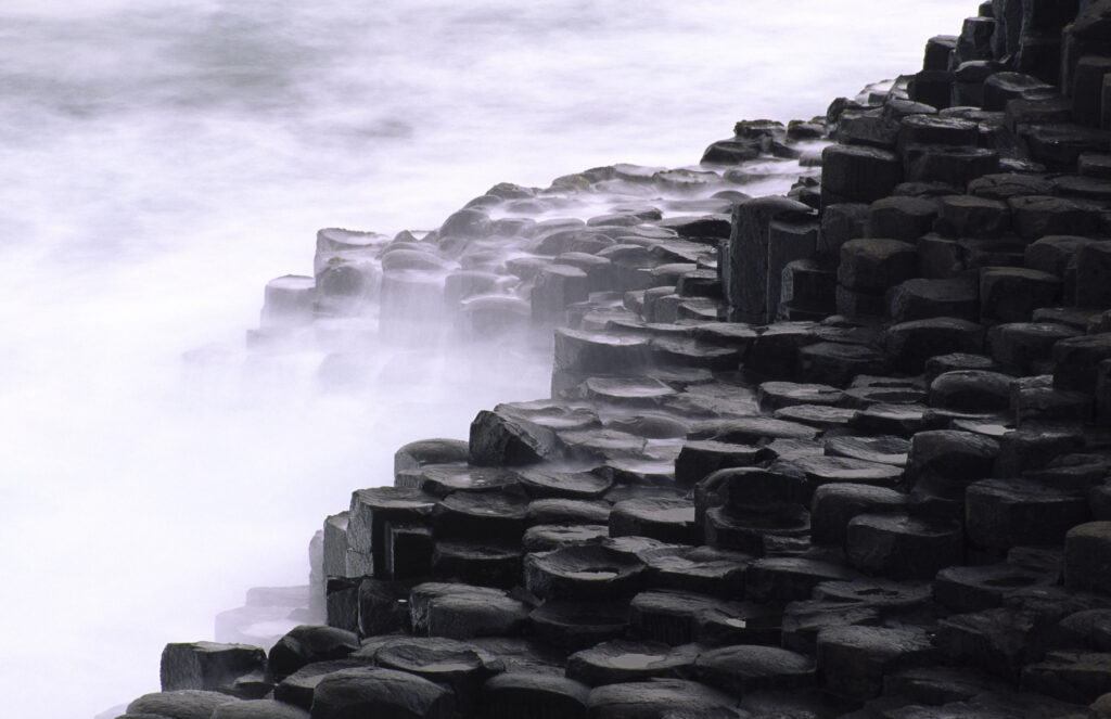 NORTHERN IRELAND, County Antrim, Giants Causeway. Waves crash against the hexagonal basalts rock formations of this world heritage site.