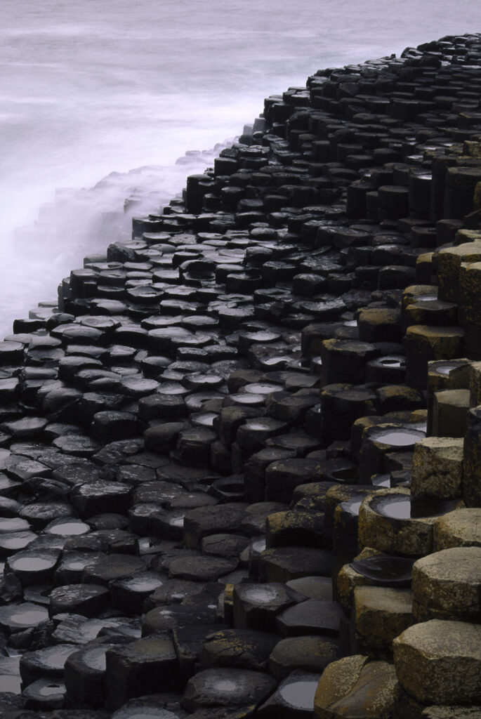 NORTHERN IRELAND, County Antrim, Giants Causeway. Waves crash against the hexagonal basalts rock formations of this world heritage site.