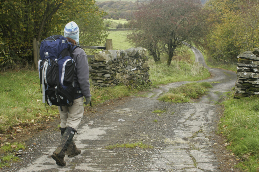 ENGLAND, Cumbria, Lake District National Park. Girl hiker walking the Cumbria Way track from High Stennerley to Kendall Ground