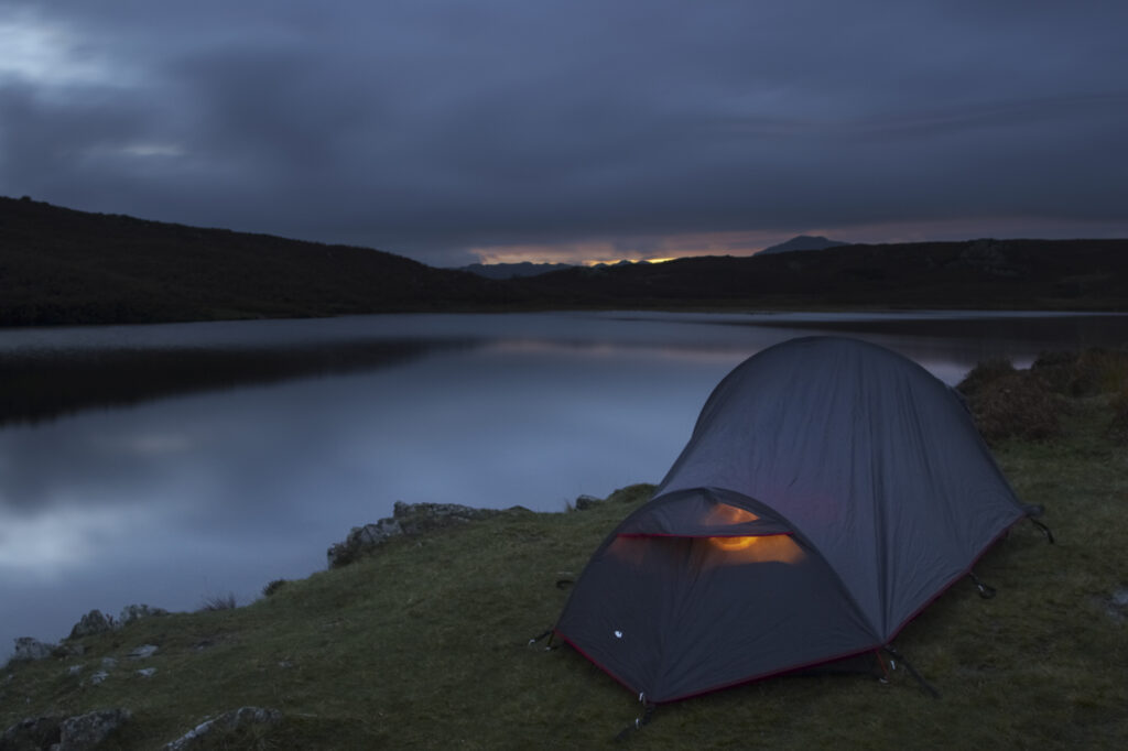 England, Cumbria, Lake District National Park. Hikers wild camping next to the still waters of Beacon Tarn on the cumbria way
