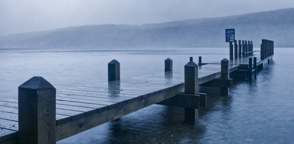 England, Cumbria, Lake District National Park. A deserted jetty stretching out towards Coniston Water on wet day on cumbria way
