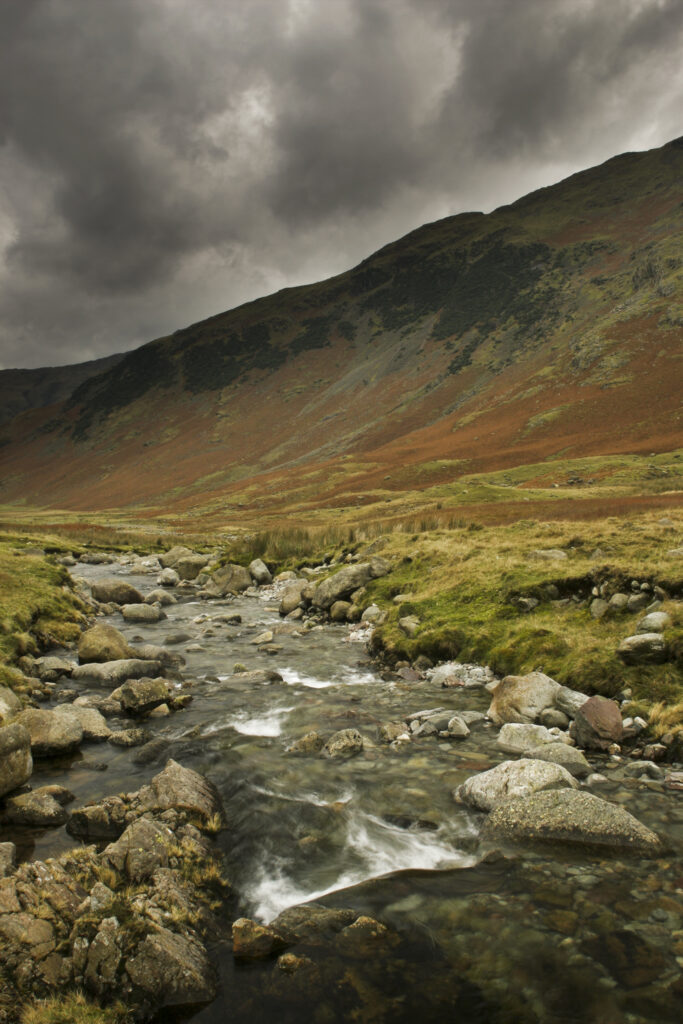 ENGLAND Cumbria Lake District National Park A small beck and red hues of the wild landscape on the Cumbria Way to Stake Pass