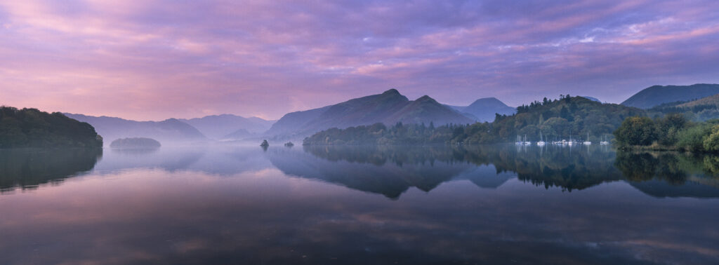 ENGLAND, Cumbria, Lake District National Park. The pastel colours of dawn, reflected in the still waters of Derwentwater.