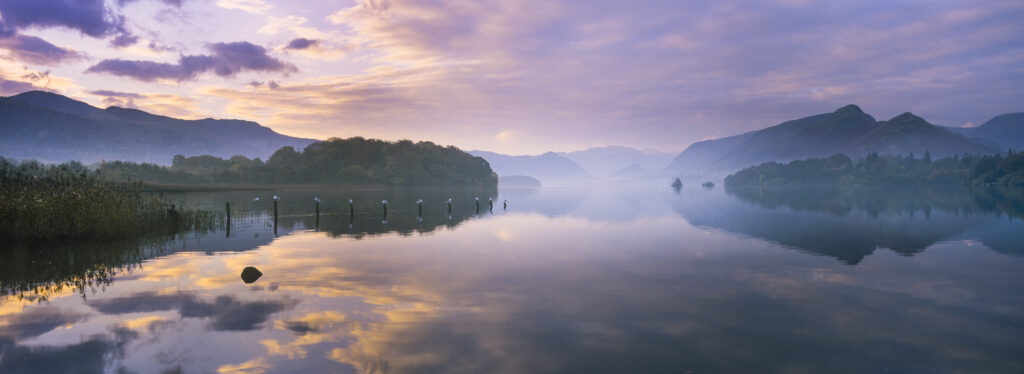 ENGLAND, Cumbria, Lake District National Park. The pastel colours of dawn, reflected in the still waters of Derwentwater.