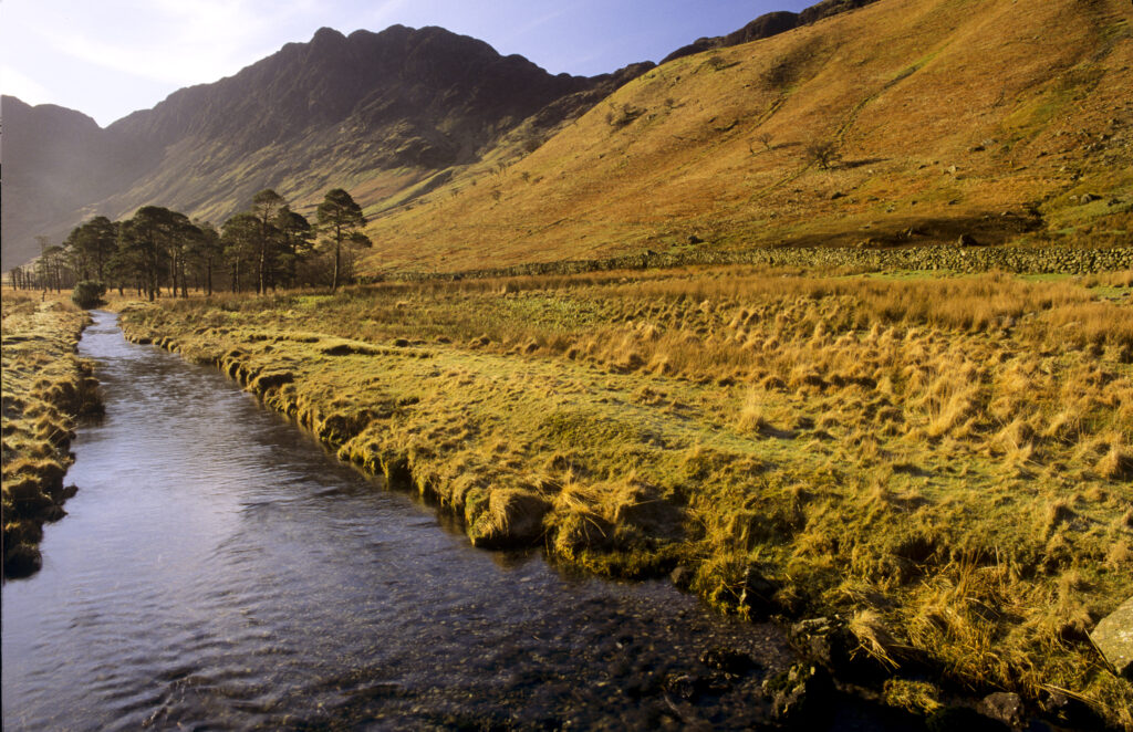 ENGLAND, Cumbria, Lake District National Park. The surrounding landscape of Peggy's Bridge with Fleetwith Pike in the distance.