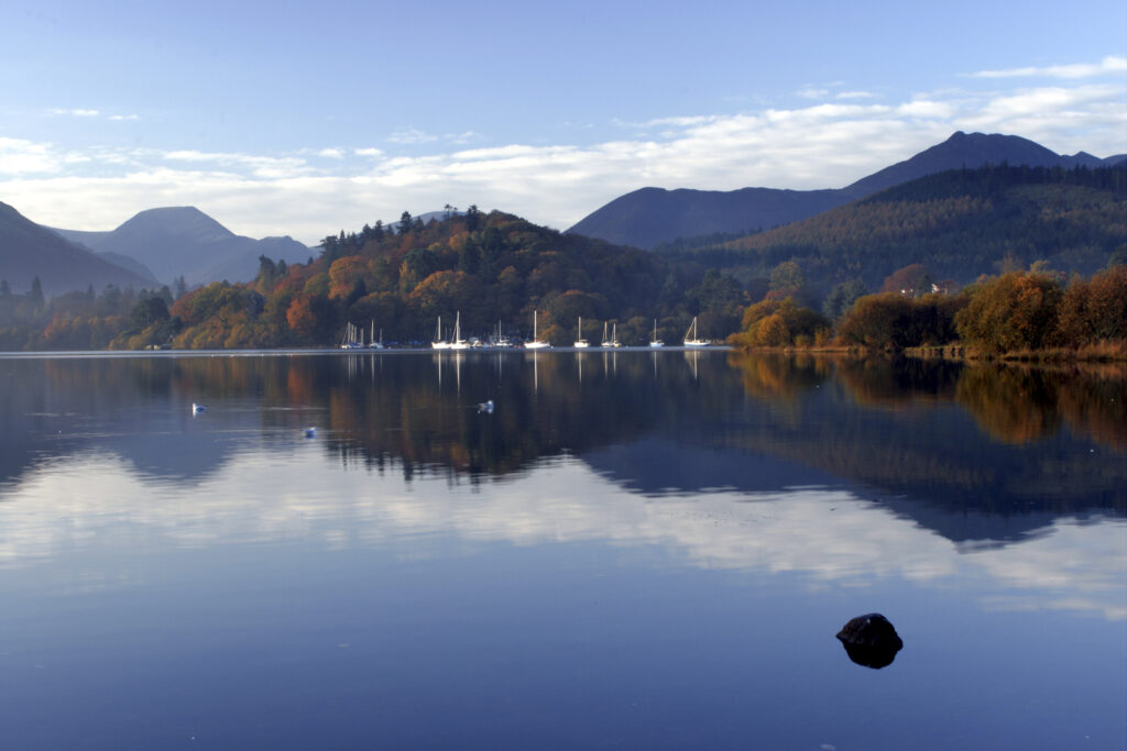 ENGLAND Cumbria Lake District National Park The surrounding autumn colours of woodland and mountain reflected in Derwentwater