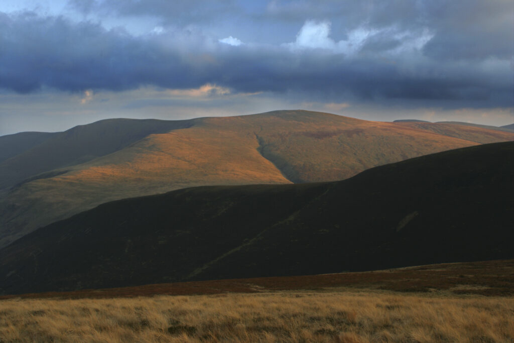 ENGLAND, Cumbria, Lake District National Park. The soft hues of a sunset illuminate the hills of Caldbeck common