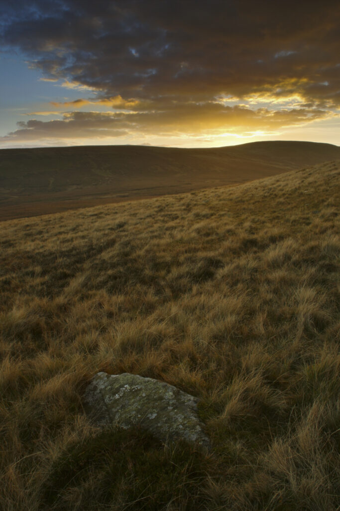 ENGLAND, Cumbria, Lake District National Park. The soft hues of a sunset behind the hills of Caldbeck common