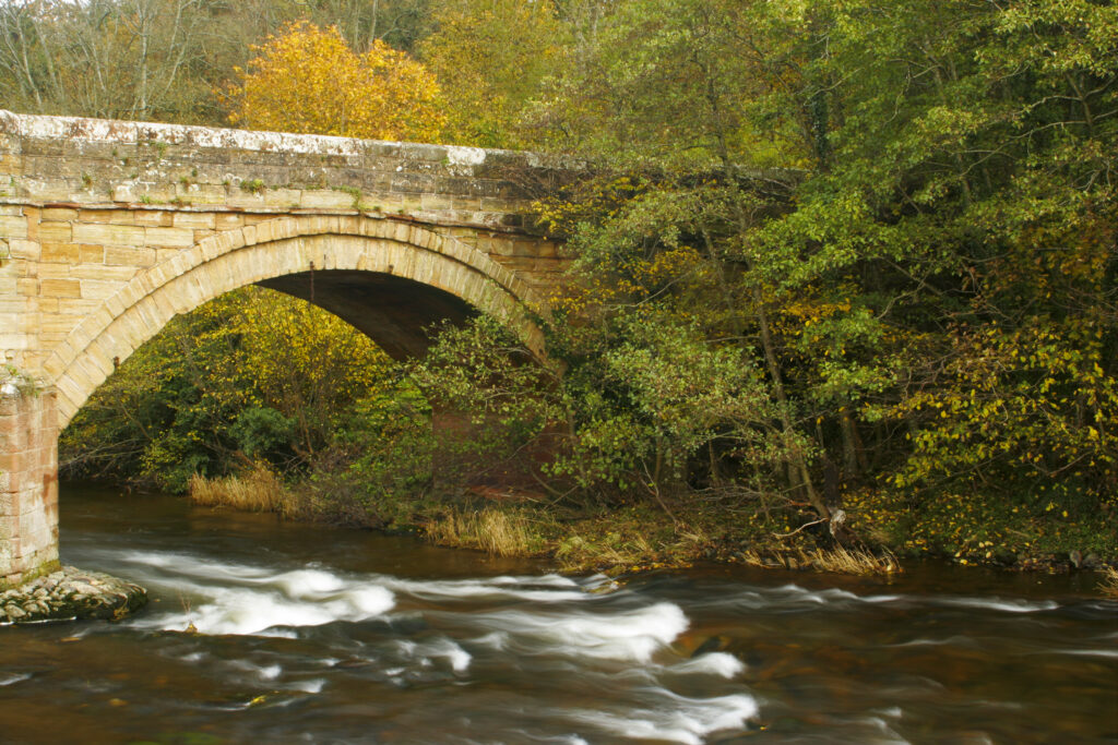 ENGLAND, Cumbria, Lake District National Park. The fast flowing waters of the River Caldew running below Rose Bridge near Rose bank