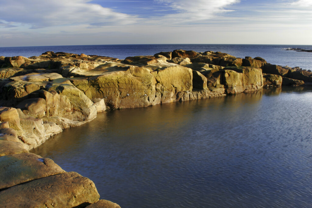 England, Tyne and Wear, Cullercoats. A swimming and bathing pool cut into the rocky coastline of the North Sea in North Tyneside.