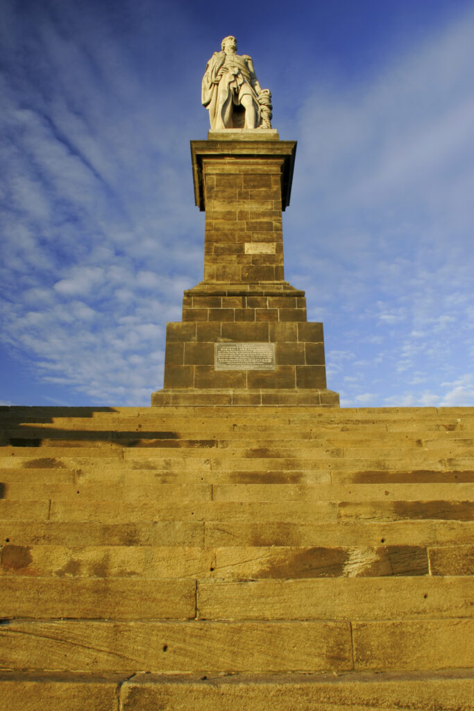 ENGLAND, Tyne and wear, Tynemouth. The setting sun iluminates the Collingwood monument and cannons