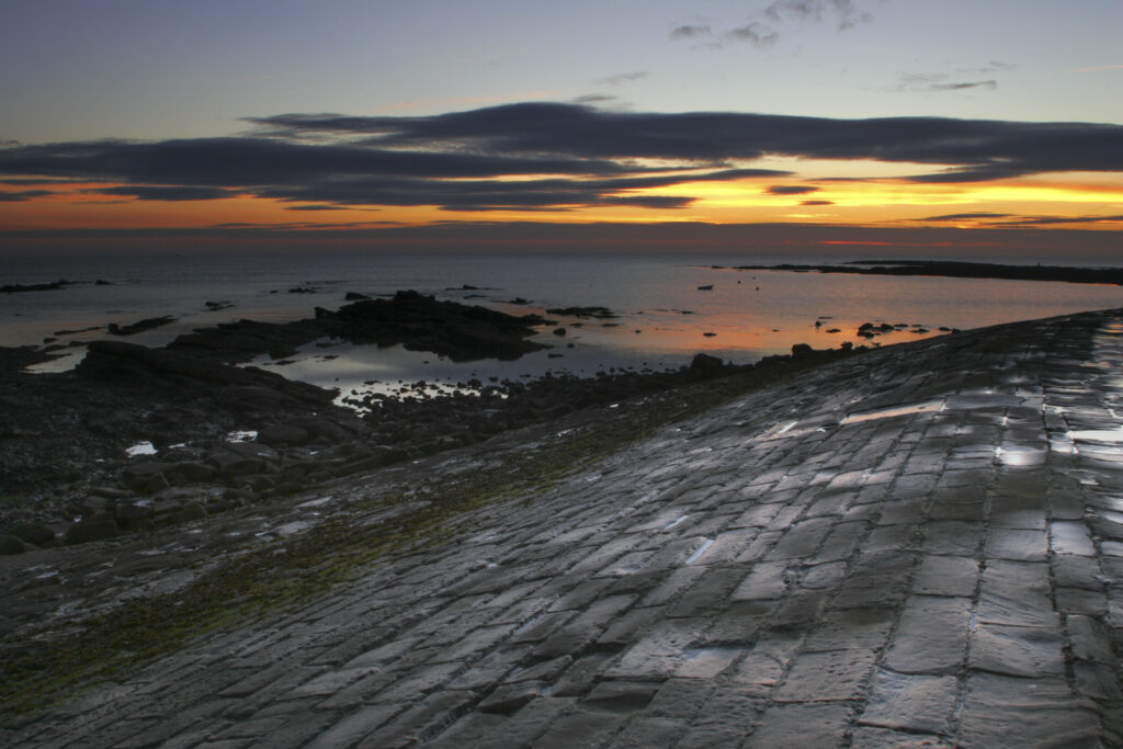 England, Tyne and Wear, Cullercoats. Sunrise viewed from the North Jetty in Cullercoats Bay.