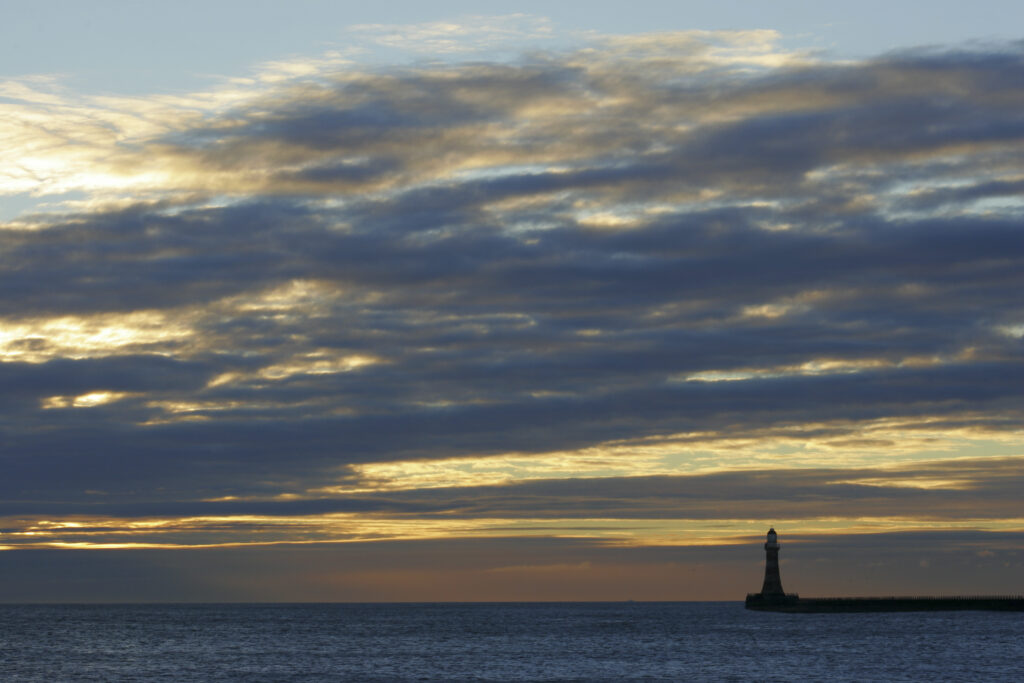 England, Tyne and Wear, Seaburn. Dawn looking across the North Sea towards the Roker pier and lighthouse