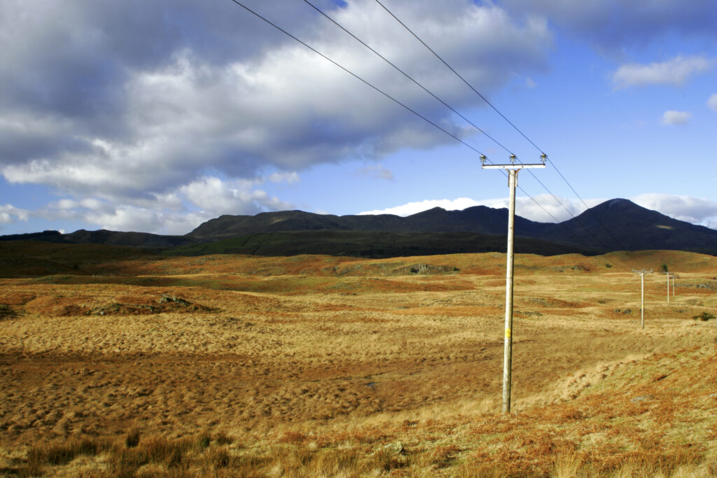 England, Cumbria, Lake District National Park. Power lines run across the remote landscape of Torver Common on the Cumbria Way