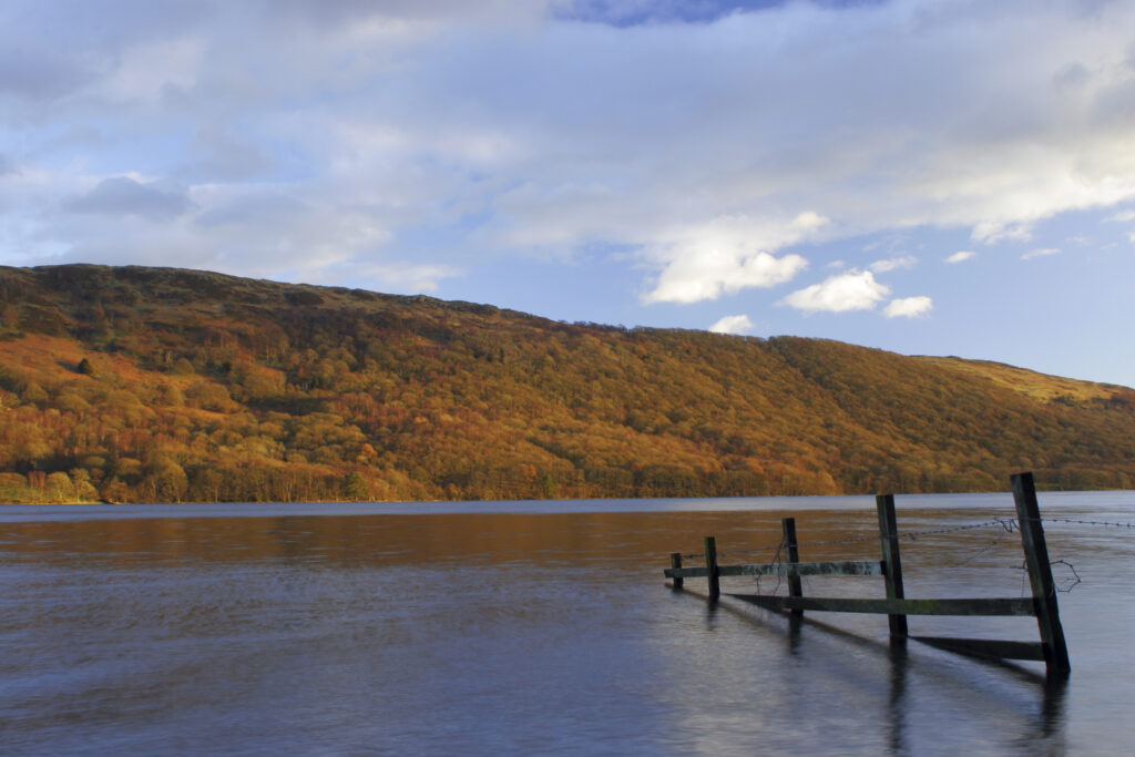 ENGLAND, Cumbria, Lake District National Park. Afternoon light illuminates the calm waters of Coniston Water on the Cumbria Way