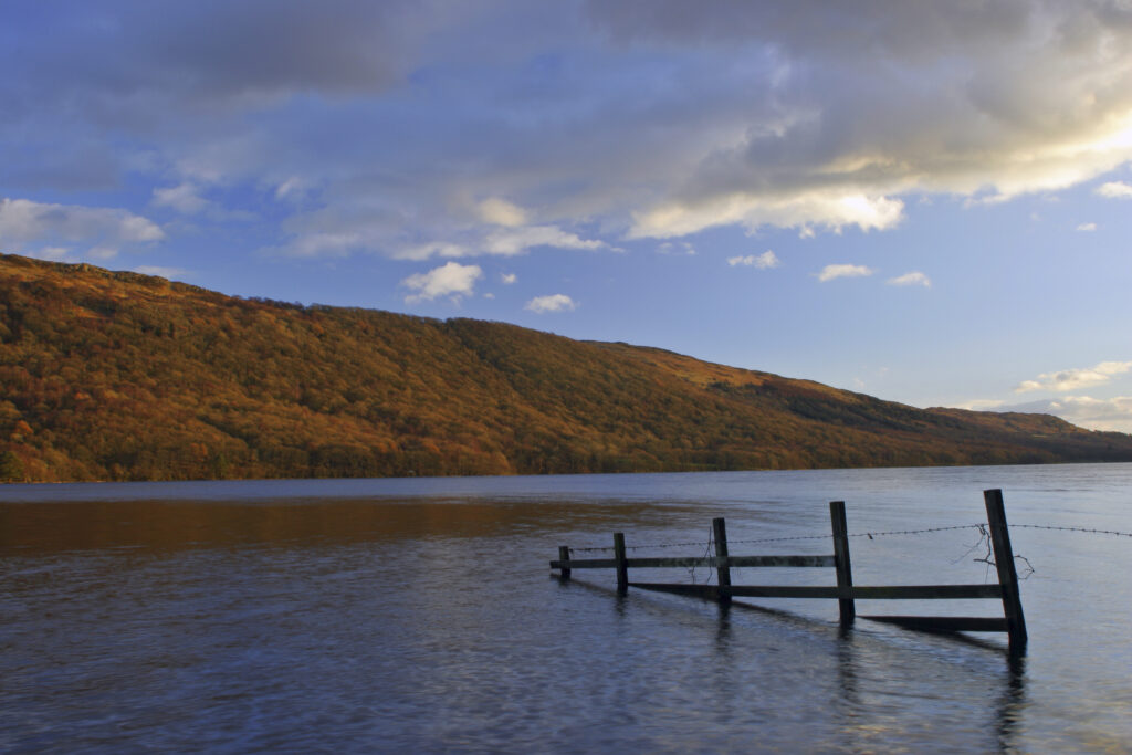 ENGLAND, Cumbria, Lake District National Park. Afternoon light illuminates the calm waters of Coniston Water on the Cumbria Way