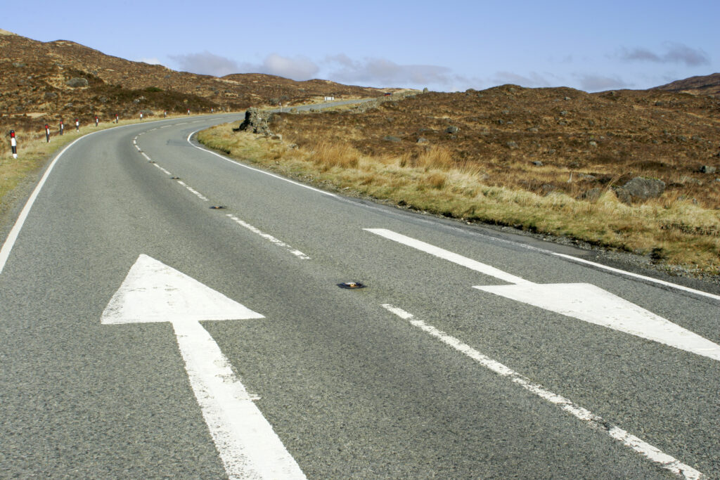 Scotland, The Isle of Skye, Sligachan. Direction arrows painted on the A850 road running through Sligachan.