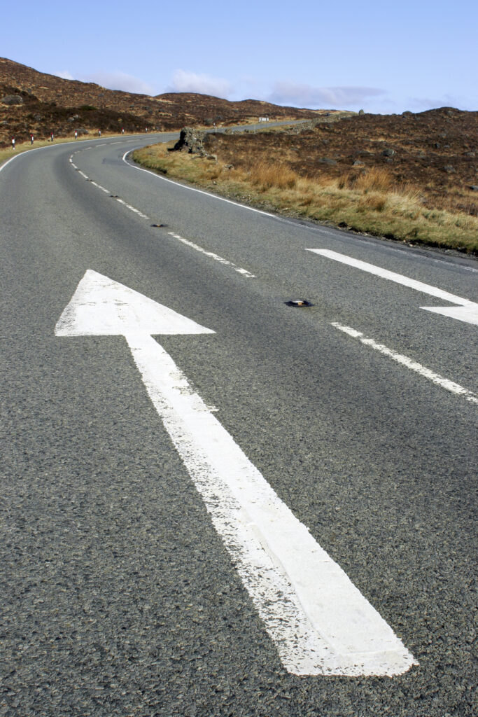 Scotland, The Isle of Skye, Sligachan. Direction arrows painted on the A850 road running through Sligachan.